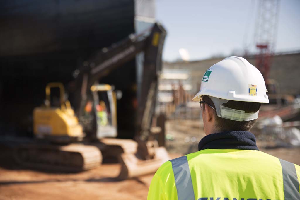 Female supervisor inspecting work on a digger
