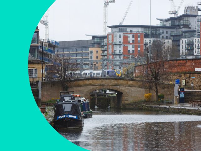 Train approaching Leeds station with canal in foreground