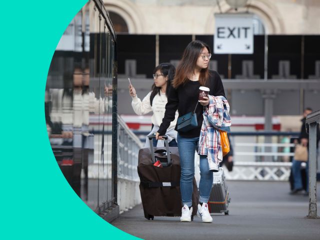 Two people walking across a bridge at a station