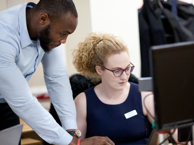 Two TfN colleagues talking at computer