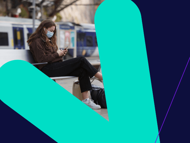 Female in mask on phone on bench at station