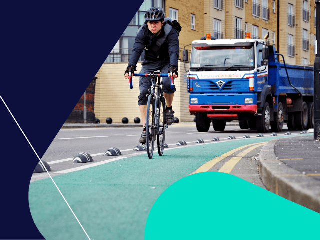 male cycling in cycle lane large truck in background on road