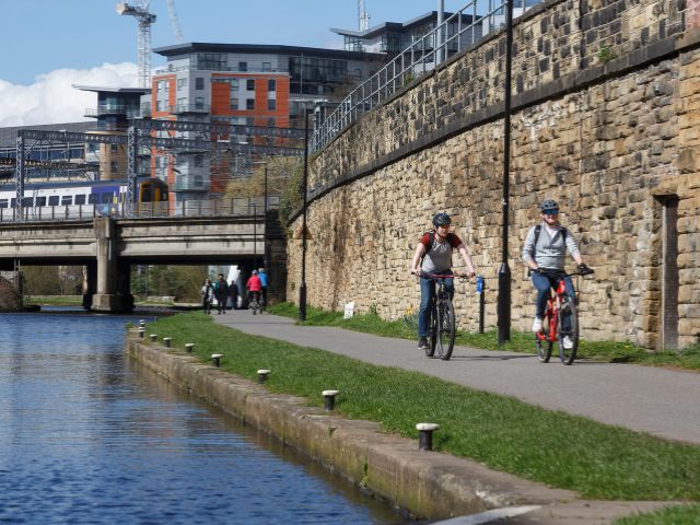 Cyclists on canal path with Northern train in the background